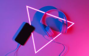 Headphones and a smartphone are placed next to a brightly lit triangular design